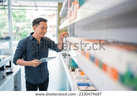 male shopkeeper checking the liquid stock at the shelf using the digital tablet