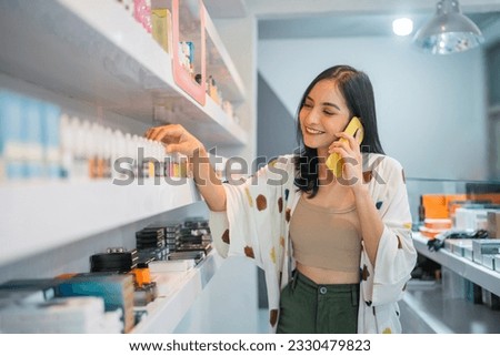 female vape seller observing the liquid stock at the shelf while calling on phone