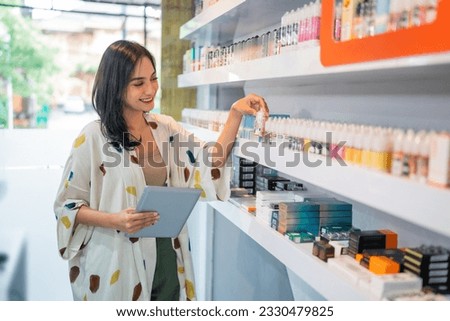 beautiful shopkeeper observing the liquid stock using the digital tablet