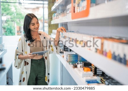 female seller checking the liquid stock at the shelf using the digital tablet