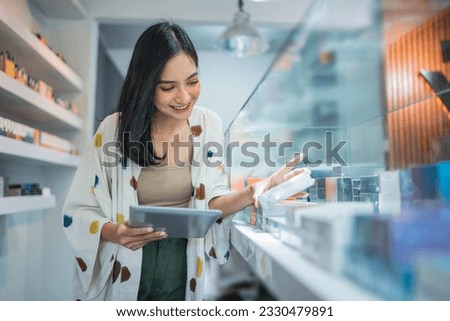 female seller checking the vape mods inside the display table using the digital tablet