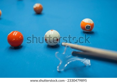 portrait of the cue stick poking the white ball helped by the bridge at the billiard game Royalty-Free Stock Photo #2330479895