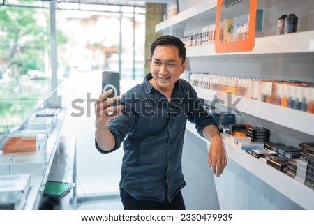 male vape seller taking selfie photo using the phone while standing beside the store shelf