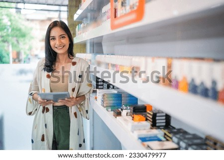 beautiful shopkeeper standing holding the digital tablet beside the vape store shelf
