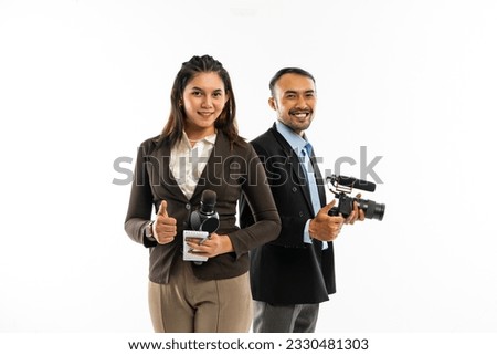 a beautiful journalist in brown blazer standing with thumb up with a male journalist standing behind and smiling Royalty-Free Stock Photo #2330481303