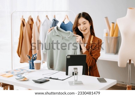 Fashion blogger concept, Young Asian women selling clothes on video streaming.Startup small business SME, using smartphone or tablet taking receive and checking in home office
 Royalty-Free Stock Photo #2330481479
