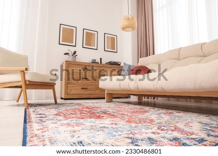 Beautiful rug, sofa, armchair and chest of drawers indoors, low angle view Royalty-Free Stock Photo #2330486801