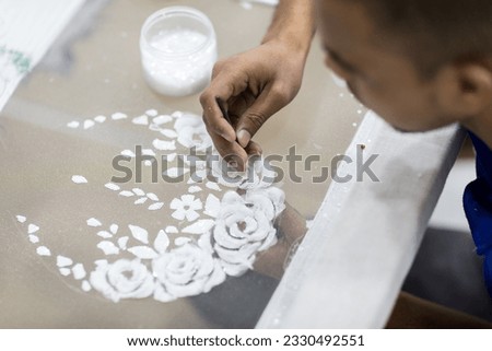 Detail closeup of handicrafts tailor embroidering floral patterns onto tulle fabric at the factory. Royalty-Free Stock Photo #2330492551