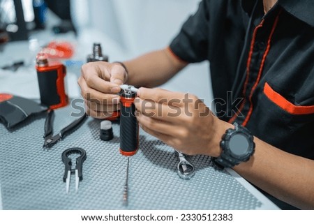 the hands of male vape seller changing the vape cotton at the vape store