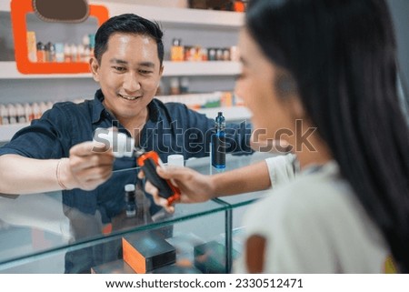 male shopkeeper helping the female customer to refill the liquid at the vape mod