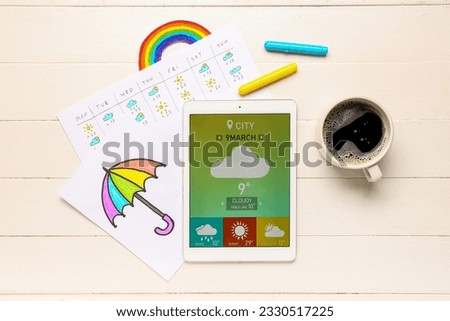 Tablet computer with weather forecast, drawn umbrella and cup of coffee on white wooden background