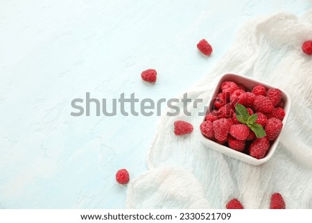 Bowl with fresh raspberry and mint on light background