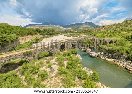 Drone view of the Mesi Bridge, located in Albania, is an architectural gem that spans the Kir River in the picturesque village of Mesi. This historic stone bridge, dating back to the Ottoman period. Royalty-Free Stock Photo #2330524547