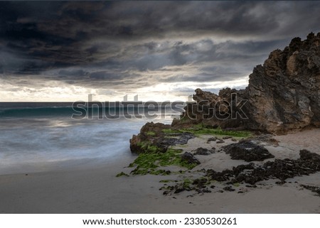 Beautiful stormy scene, rocks, waves and ominous cloudy sky.