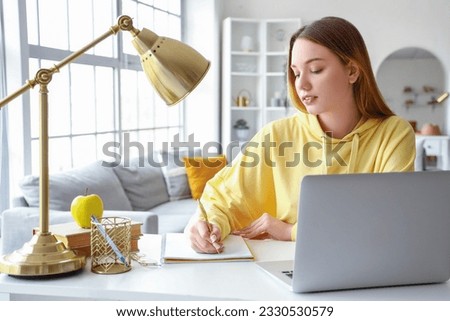 Female student writing in notebook at home