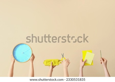 Many hands holding school supplies on beige background