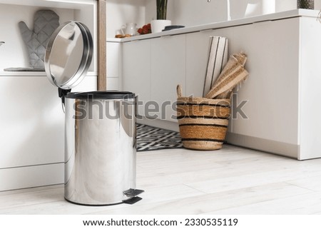 Opened metallic trash bin near table in interior of modern kitchen Royalty-Free Stock Photo #2330535119