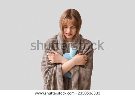 Ill teenage girl with hot water bottle on light background