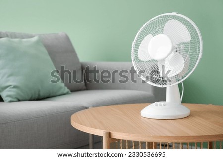 Wooden table with modern electric fan in interior of living room Royalty-Free Stock Photo #2330536695