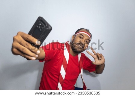 Asian man make selfie photo with Indonesian independence attribute