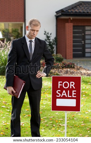Realtor standing in front of house for sale