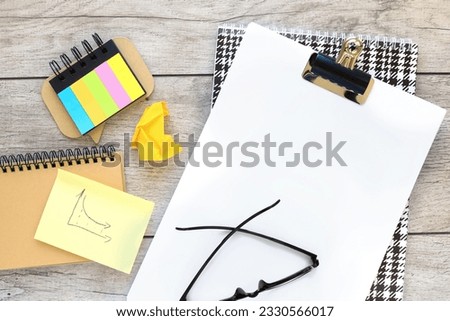 A blank sheet of a4 paper on a wooden table. stickers and a notebook with a spring. Top view, flat lay.