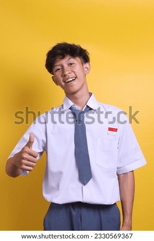 Indonesian senior high school student wearing uniform showing thumbs up sign gesture