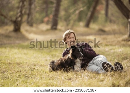 Mature man spending time with his dog in the forest Royalty-Free Stock Photo #2330591387