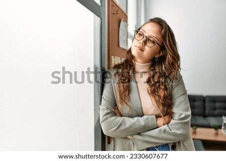 Young beautiful hispanic woman business worker standing with arms crossed gesture at office