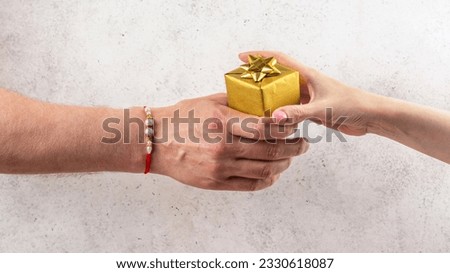 Happy Raksha Bandhan Holiday Background. Indian brother wearing rakhi bracelet is giving gift box to his sister. Royalty-Free Stock Photo #2330618087