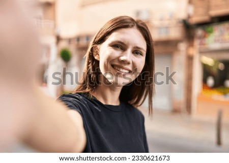 Young blonde woman smiling confident making selfie by the camera at street