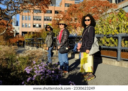 Asian female tourists enjoying the scene of the beautiful fall foliage at the High Line in New York City, USA.