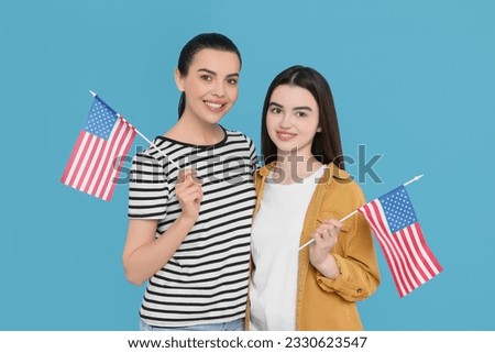 4th of July - Independence Day of USA. Happy woman and her daughter with American flags on light blue background