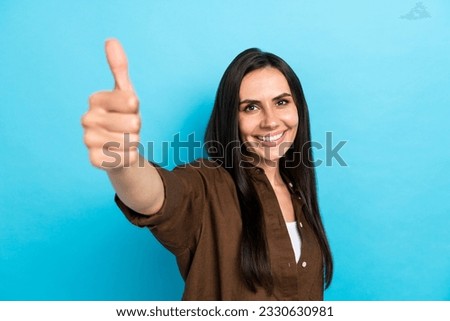 Portrait photo of funny cute girl appoint good quality product raising thumb finger up to camera isolated blue color background