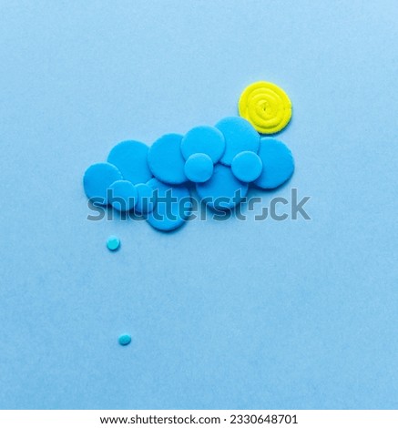 Plasticine sun with cloud and rain. Modeling clay handmade weather on blue background.