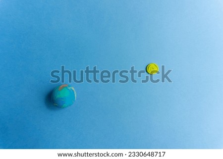 Plasticine model of planet Earth on blue background and sun, cosmos