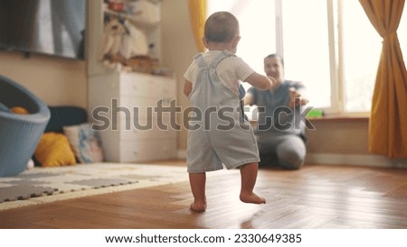 baby first steps. baby goes her father at window learns to walk to take first steps. happy family kid dream concept. dad calls son baby first steps indoors. happy family lifestyle indoors concept Royalty-Free Stock Photo #2330649385