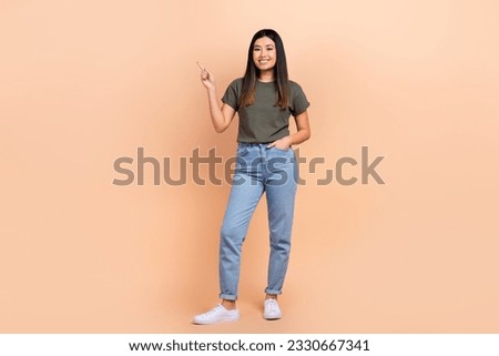 Full body photo of korean girl wear casual outfit jeans khaki t-shirt point finger mockup brand store isolated on beige color background