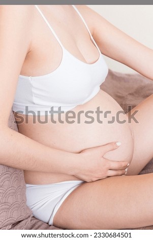 Pretty pregnant woman hands massaging leg sitting on bed.