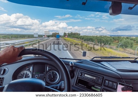 View of the road from the driving position of a truck of a landscape with clouds. Royalty-Free Stock Photo #2330686605