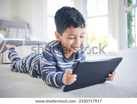 Young boy, tablet and games or cartoon streaming online with internet, e learning and relax on carpet in house. Watch animation film, male kid at home and connection, entertainment and subscription