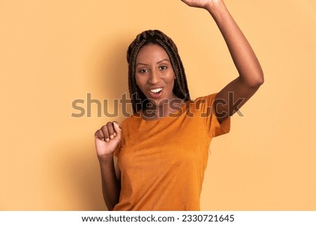 excited black woman raising arms and celebrating in all beige colors. celebration, positive, success concept.