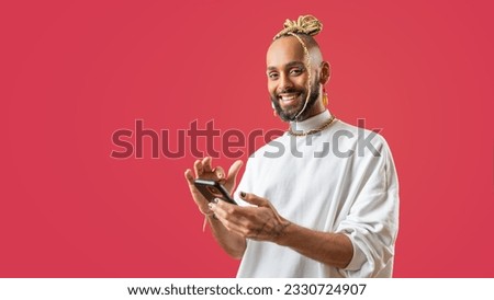 Trendy black latin gay man in white clothes use smartphone looking at camera on pink background studio portrait People lifestyle fashion lgbtq concept Royalty-Free Stock Photo #2330724907