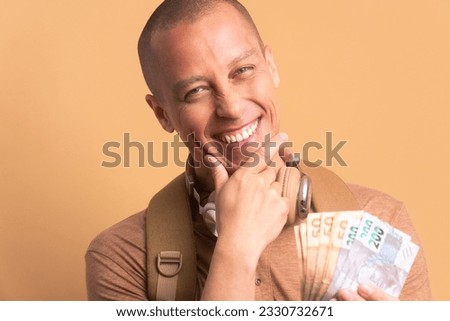 joyful bald man showing money, brazilian currency in beige background. business, loan, pay, wealth concept.