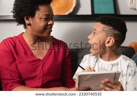 Young boy understands exercise and looks at mother in living room at home Royalty-Free Stock Photo #2330740535