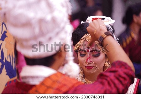 The groom rubs vermilion on the bride's forehead Royalty-Free Stock Photo #2330746311