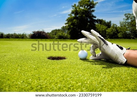 Golfer flicking golf ball into hole