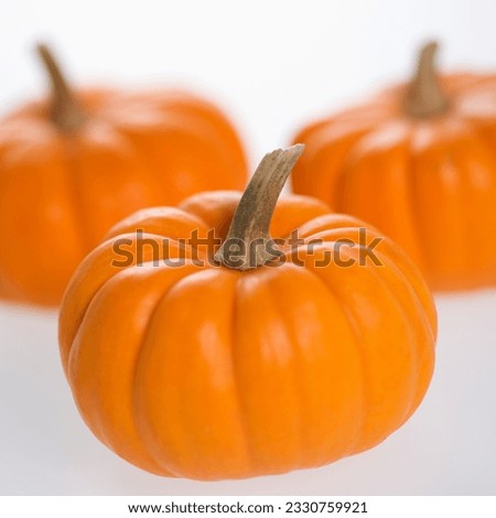 Still life of three orange pumpkins against white background.