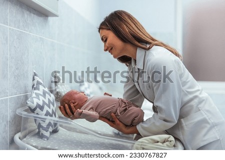 Pediatrician taking care of newborn baby at hospital ward. A female nurse of is holding a newborn baby at the hospital. They baby is sleeping. Premature born baby and nurse in hospital crib Royalty-Free Stock Photo #2330767827
