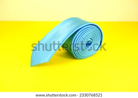 rolled blue tie isolated on yellow background close up shot single object concept nobody 